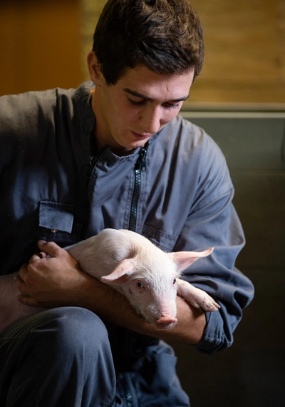 Éleveur de porc tenant un cochon dans ses bras